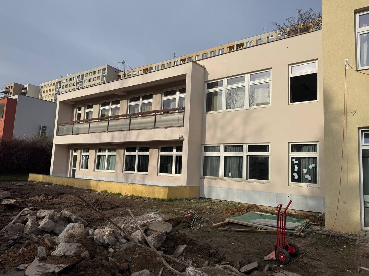 Hotová fasáda po sejmutí lešení: světlá omítka, ochoz v patře a nové soklové zakončení.